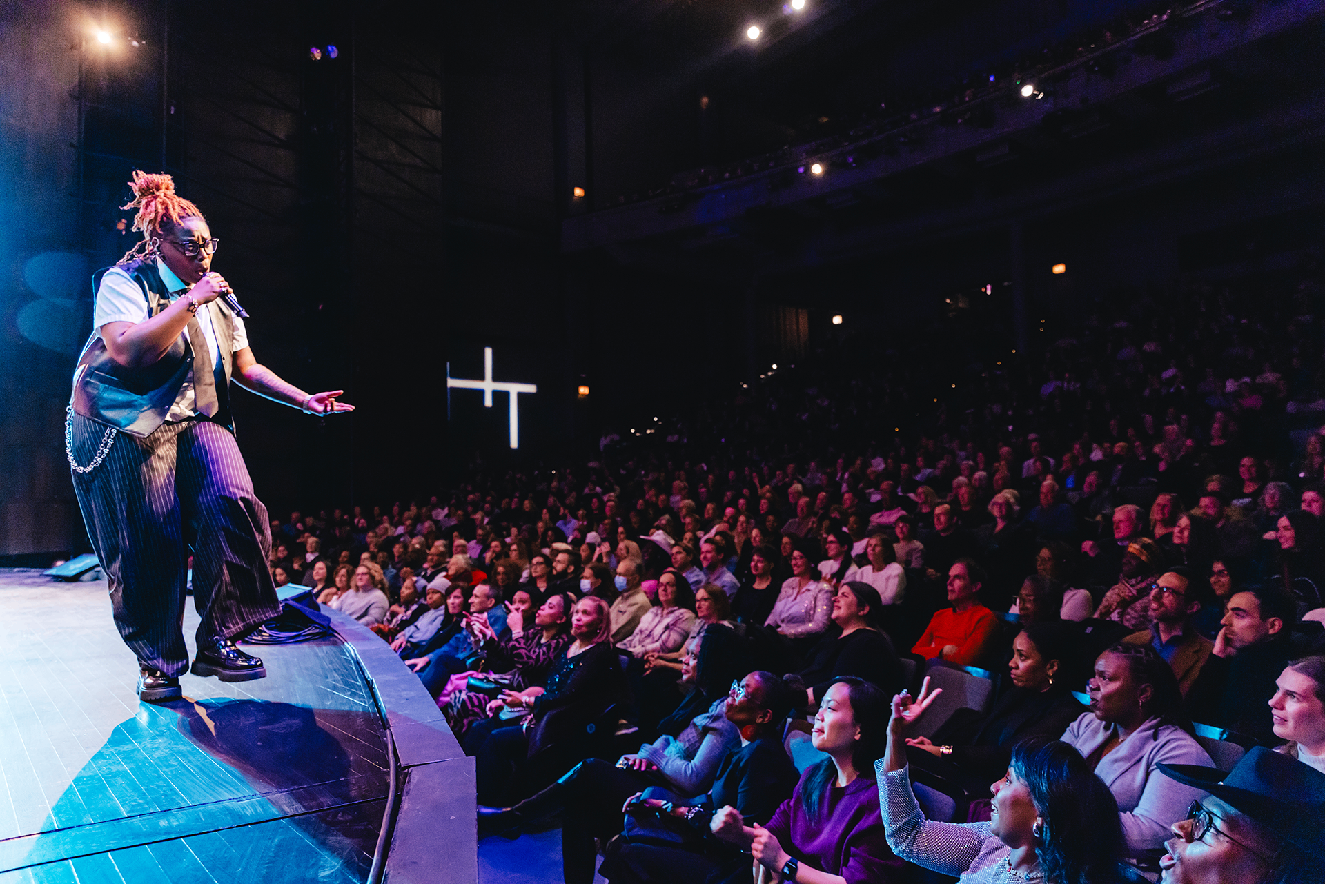 Singer performing on stage to a packed theater audience