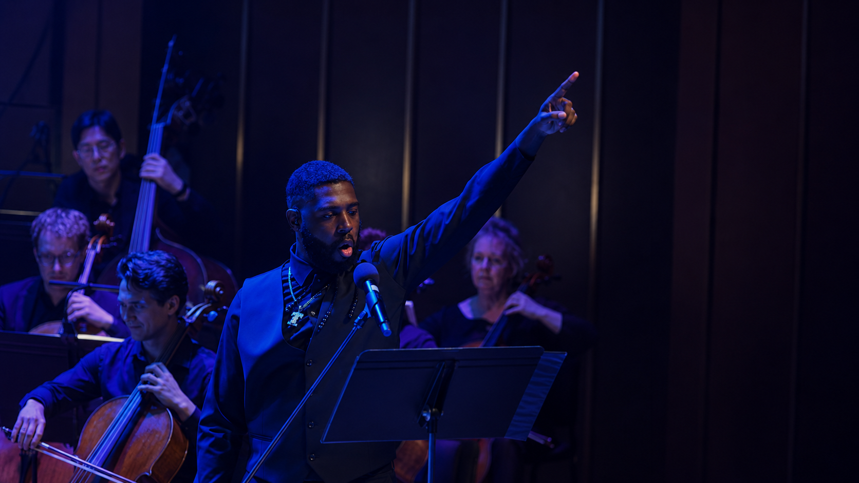 A vocalist mid-performance with full orchestra at a SymphonyFuse concert